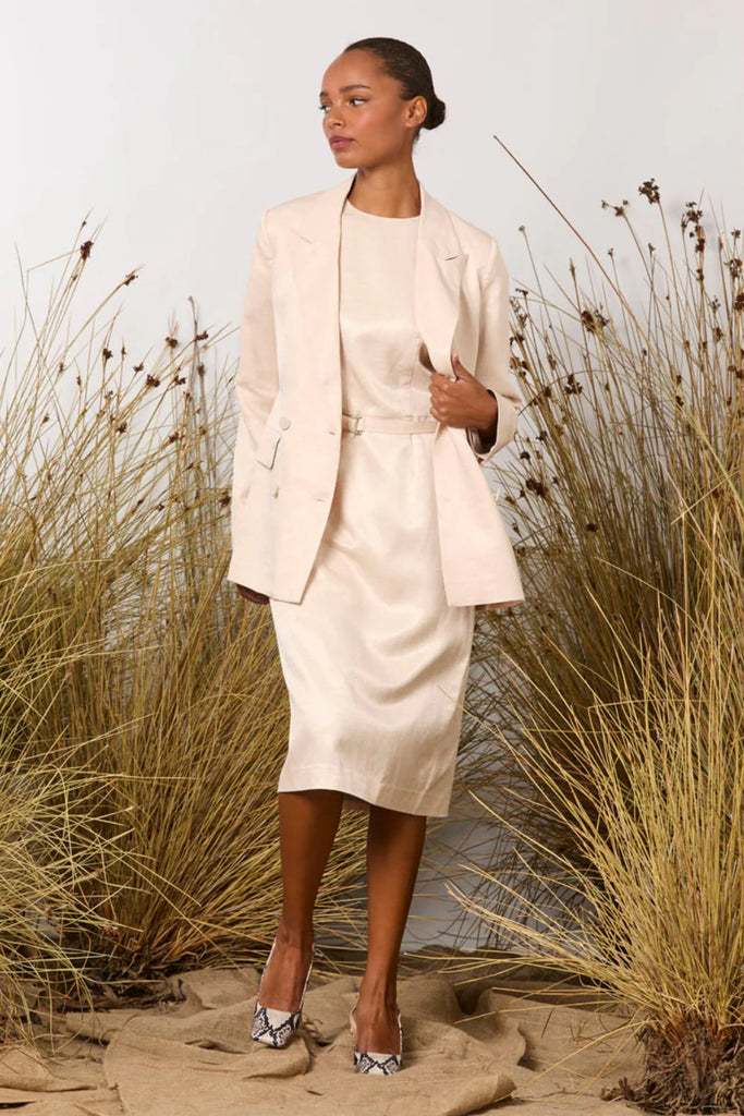 Woman in a M A Dainty Dynasty light pink jacket standing in a natural setting with tall grasses.